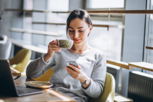 woman-sitting-cafe-drinking-coffee-working-computer